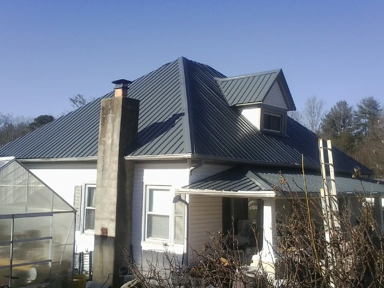 Dark blue standing seam metal roof on a white farmhouse with dormer — Slate & Tile Roof Repair by Roofing Brothers in Wheeling